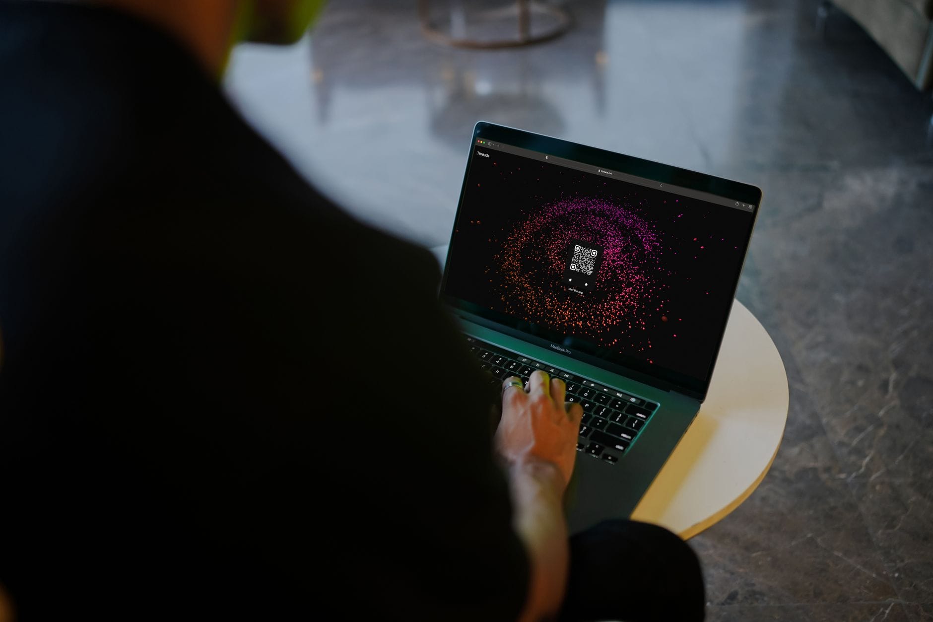 Osoba skanuje kolorowy kod QR na ekranie laptopa w nowoczesnym wnętrzu