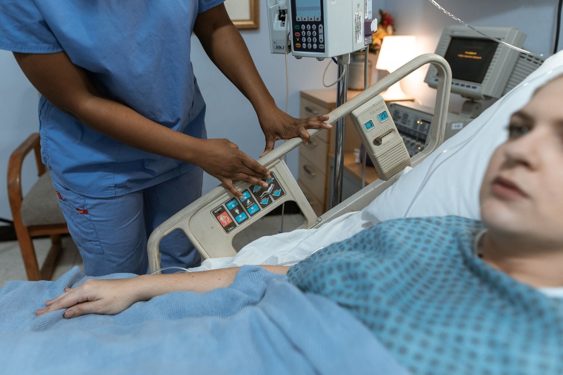 Pielęgniarka w scrubs pomaga pacjentowi na łóżku rehabilitacyjnym