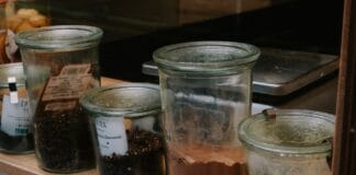 Jak przechowywać przyprawy w domu, aby długo zachowały smak i aromat Szklane słoiki z różnymi przyprawami ustawione równo na kuchennej półce