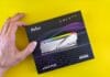 Ile pamięci RAM do gier w 2025 roku: 16 GB, 32 GB czy 64 GB? Dłoń trzymająca opakowanie pamięci RAM Netac DDR5 na żółtym tle